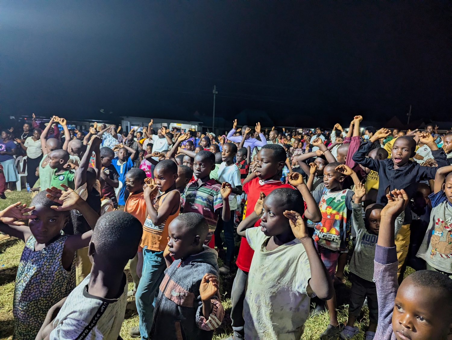 An evening congregation with hands raised during the service.